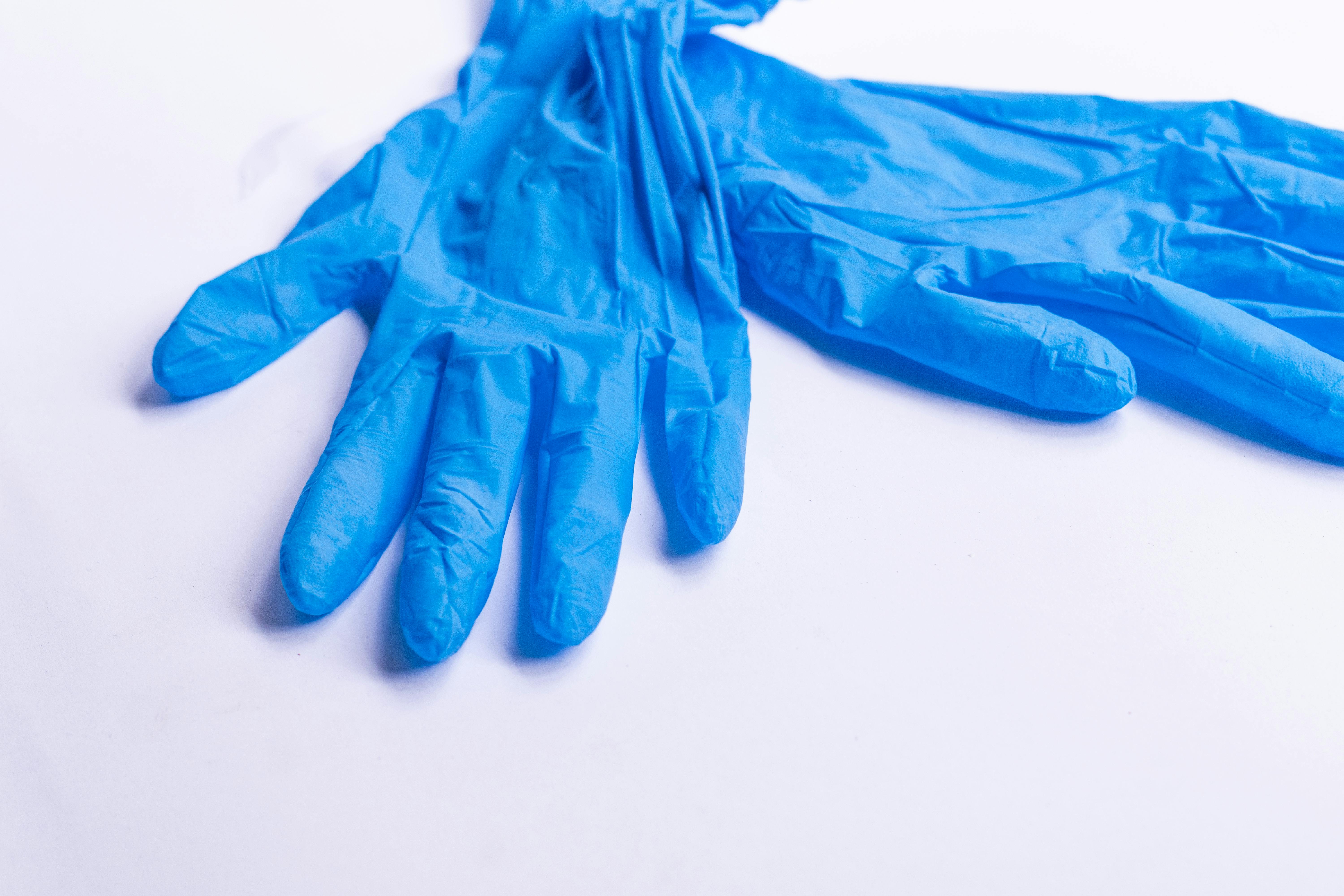 Pair of blue disposable medical latex gloves for protection placed on white background in light room of hospital